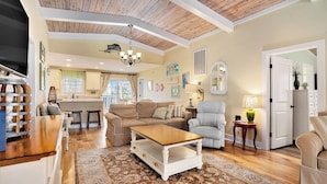 A spacious living room with a wooden ceiling, a large coffee table, and a cozy seating area. - On Point: Private Pool Across From Beach (Murrells Inlet)