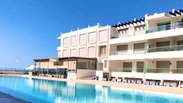 Un hôtel doté d’une longue piscine, de nombreux balcons et offrant une vue dégagée sur la mer.