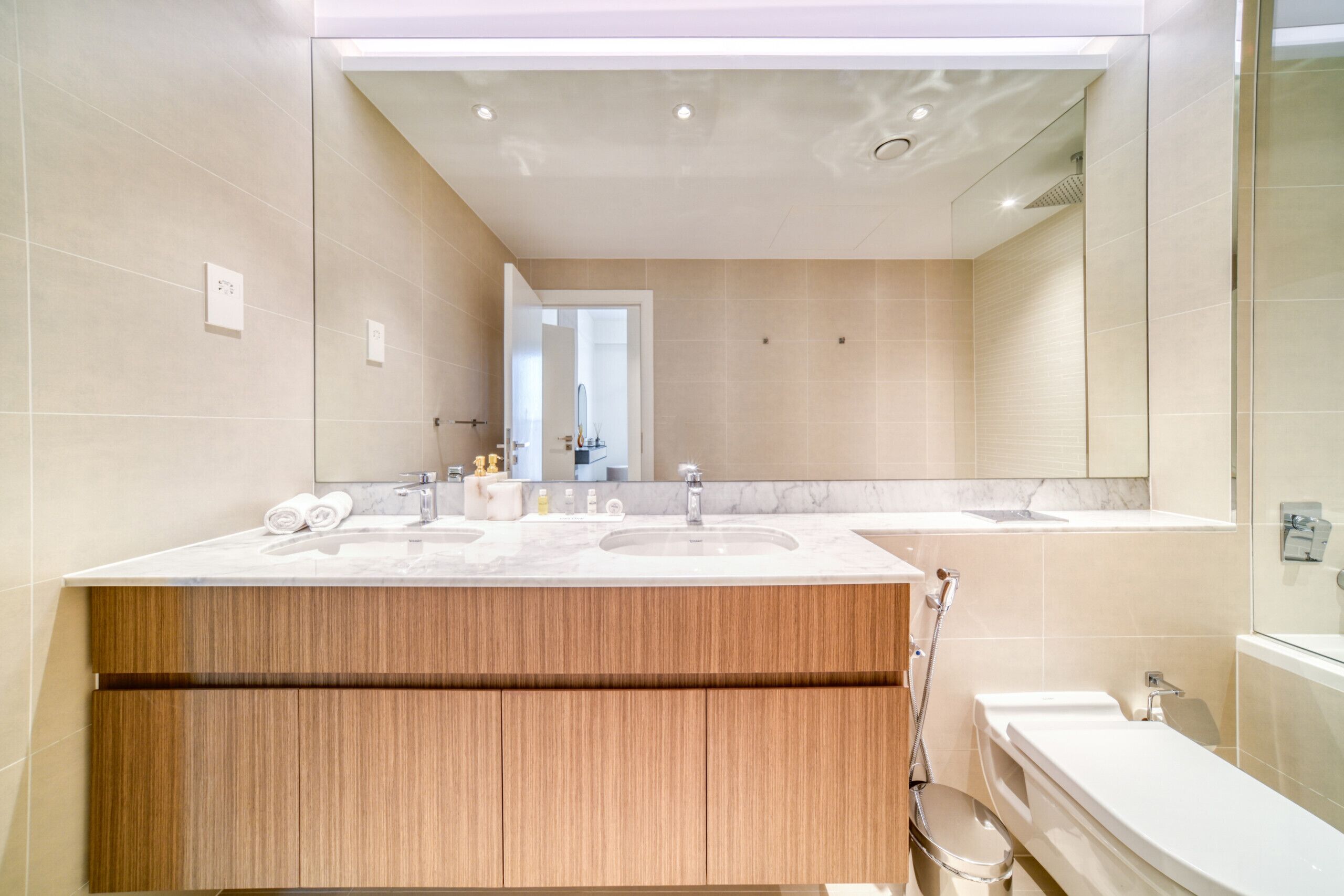 Een moderne badkamer met twee wasbakken, een grote spiegel en een douchehoek.