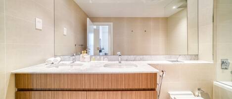 Een moderne badkamer met twee wasbakken, een grote spiegel en een douchehoek.