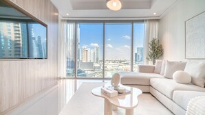 Ein modernes Wohnzimmer mit einem großen Fenster, einem Flachbildfernseher, einer Couch und einem Couchtisch.