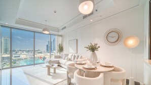 Ein modernes Wohnzimmer mit großem Fenster, einer Sofagarnitur, einem Esstisch mit Stühlen und einer dekorativen Vase.