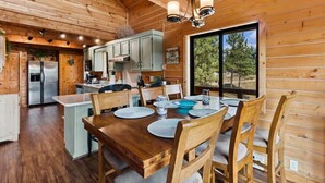 A wooden cabin interior with a dining area, kitchen, and large windows. - Lakeside Retreat in Eureka! (Eureka)