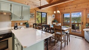 A wooden cabin interior with a kitchen, dining area, and large windows offering scenic views. - Lakeside Retreat in Eureka! (Eureka)