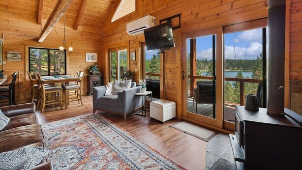 A wooden cabin interior with a dining area, sofa, and a fireplace. - Lakeside Retreat in Eureka! (Eureka)