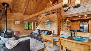 A wooden cabin interior with a living area, kitchen, and a staircase leading to an upper level. - Lakeside Retreat in Eureka! (Eureka)