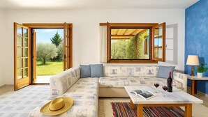 Een moderne woonkamer met een hoekbank, een salontafel en uitzicht op een tuin door openslaande deuren.