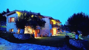 Een stenen huis met een balkon, een verharde oprit en een verzorgd gazon.