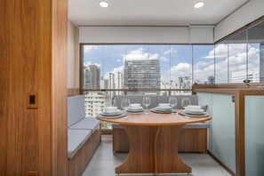 A modern dining area with a round table set for six, overlooking a cityscape through large windows. - D'Oru Vila Nova Conceição (São Paulo)