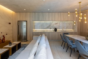 A modern kitchen with a built-in refrigerator, a marble countertop, and a dining area with a long table and chairs.