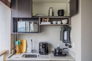 Une petite cuisine équipée comprenant un évier, une machine à café, un grille-pain, une bouilloire et un four à micro-ondes.