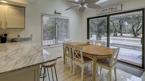 Eine Küche mit Marmorarbeitsplatte, Deckenventilator und Essbereich mit Holztisch und weißen Stühlen.