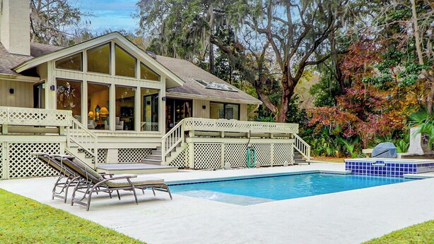 Ein Haus mit Swimmingpool, überdachter Terrasse und Blick auf Bäume.