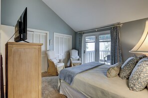 A bedroom with a bed, a wooden dresser, a chair, a television, and a window with curtains.