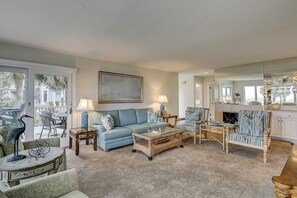 A living room with a blue sofa, a coffee table, wicker chairs, and a fireplace.