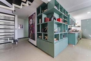 Ein modernes Interieur mit türkisfarbenen Regalelementen, einer Küchenzeile und einem großen Poster an der Wand.