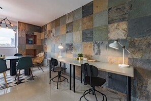 A modern dining area with a stone wall, a long table, and several chairs.
