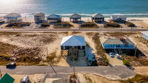 An aerial view of a coastal area with beach houses, a road, and a beach.