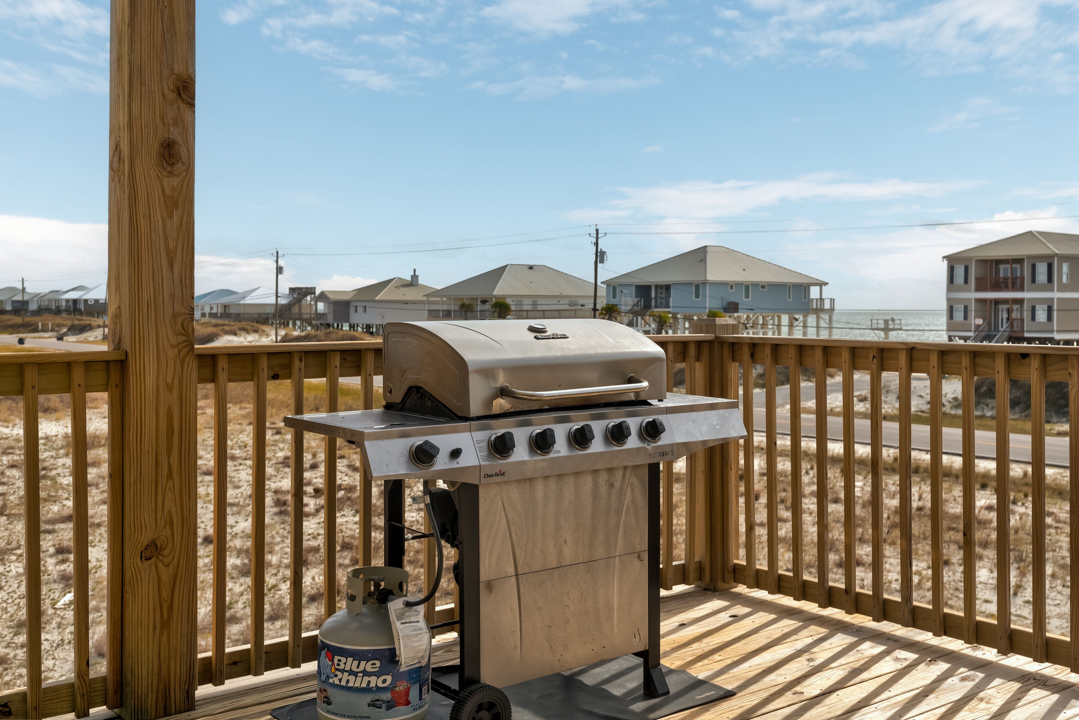 Una parrilla para barbacoa en una terraza de madera, con un tanque de propano cerca.