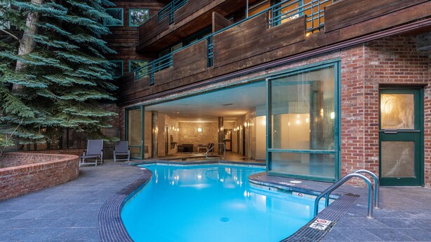 Un edificio moderno con piscina, ampie vetrate e facciata in mattoni.