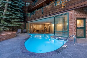 A modern building with a swimming pool, large glass windows, and a brick exterior.