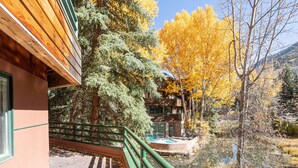 Un edificio in legno con ringhiera verde, una piscina e alberi dai colori autunnali sullo sfondo.
