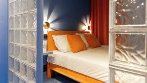 A bedroom with a wooden bed, white bedding, and orange pillows. - The Mila Brussels (Brussels)