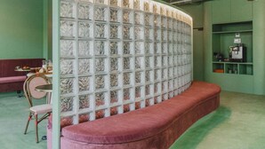 A room with a green wall, a red bench, a glass partition with a leaf pattern, and a coffee machine on a shelf. - The Mila Brussels (Brussels)