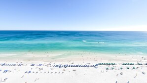 Una playa de arena blanca, agua turquesa cristalina y una hilera de sombrillas azules.
