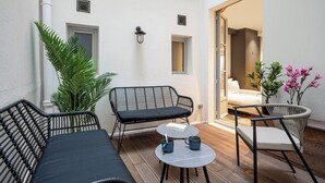 A small patio area with a sofa, two chairs, a table, and potted plants. - Saint Germain Residence (Paris)