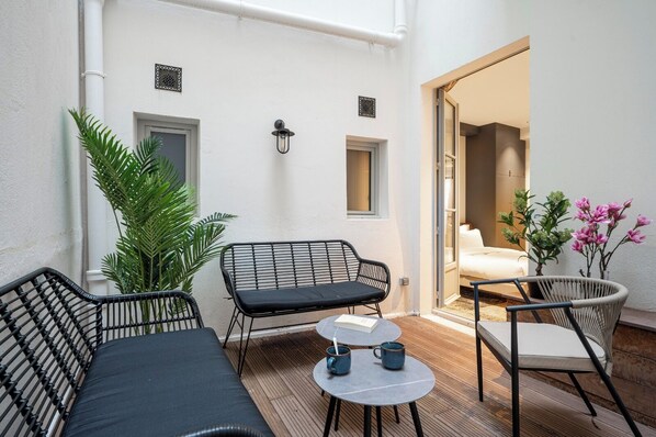 A small patio area with a sofa, two chairs, a table, and potted plants. - Saint Germain Residence (Paris)