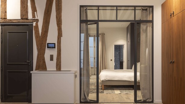 A bedroom with a bed, a wardrobe, and a sliding glass door leading to another room. - Saint Germain Residence (Paris)