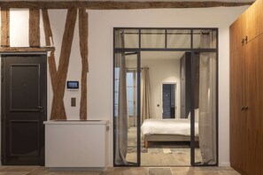 A bedroom with a bed, a wardrobe, and a sliding glass door leading to another room. - Saint Germain Residence (Paris)