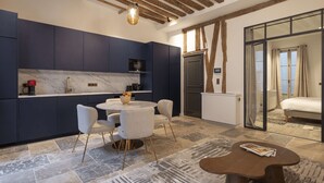 A modern kitchen with dark blue cabinets, a marble countertop, and a round dining table with chairs. - Saint Germain Residence (Paris)