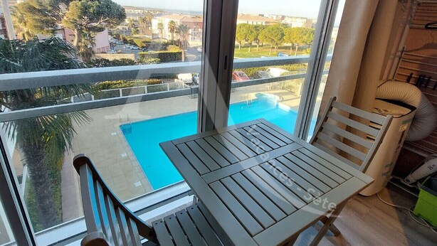A balcony with a view of a swimming pool and surrounding buildings. - T2, parking, 4 personnes, résidence avec piscine (Sète)