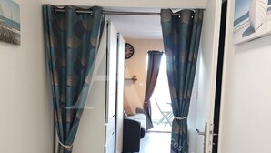 An open door leading to a living area with a sofa and a dining table. - T2, parking, 4 personnes, résidence avec piscine (Sète)