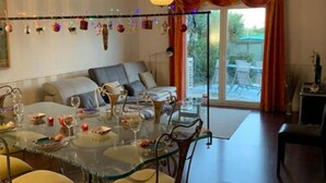 Een eetgedeelte met een glazen tafel, gele stoelen en een plafondlamp.