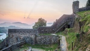 Een historisch stenen fort met een pad dat er doorheen loopt, omringd door grasvelden en een uitzicht op het landschap op de achtergrond.