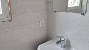Een badkamer met een witte wastafel, een spiegel en een raam.
