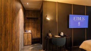 Una camera d'albergo con una parete in legno, una scrivania con il telefono, una sedia e un letto.