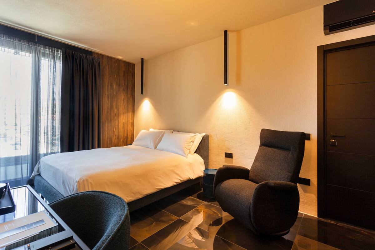 Une chambre d’hôtel moderne avec un grand lit, un bureau et une chaise.