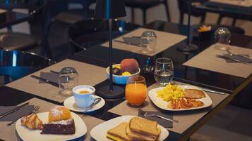 A breakfast setting with plates of toast, eggs, bacon, and a muffin.
