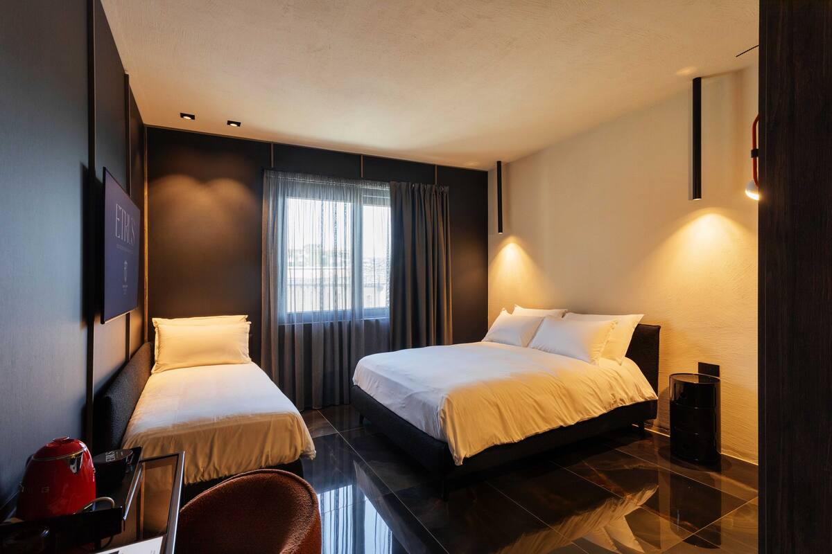 Une chambre d’hôtel avec deux lits, un bureau, une chaise et un téléviseur.