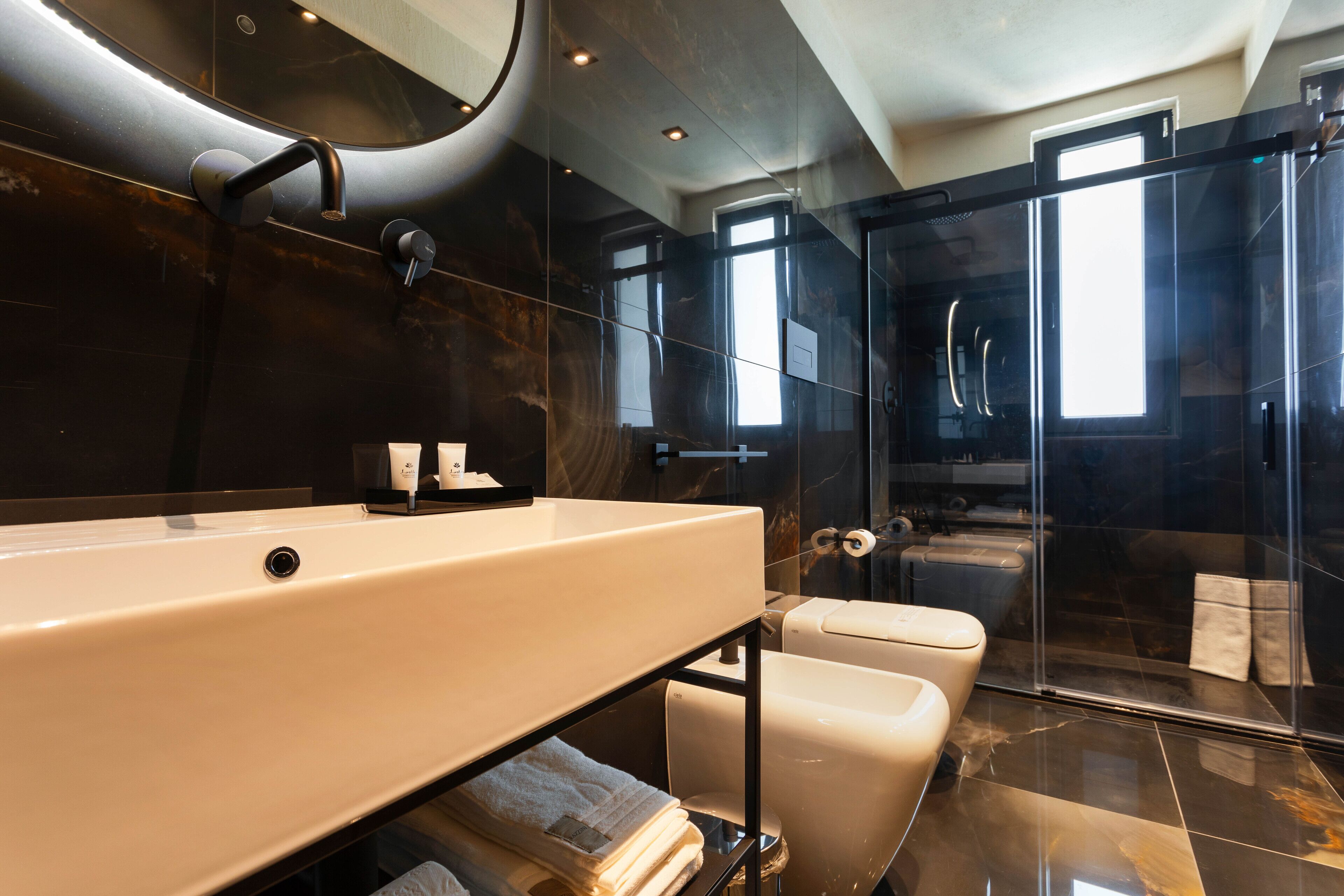 Un bagno moderno con un lavandino ampio, una cabina doccia in vetro e un water.