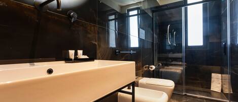 Un bagno moderno con un lavandino ampio, una cabina doccia in vetro e un water.