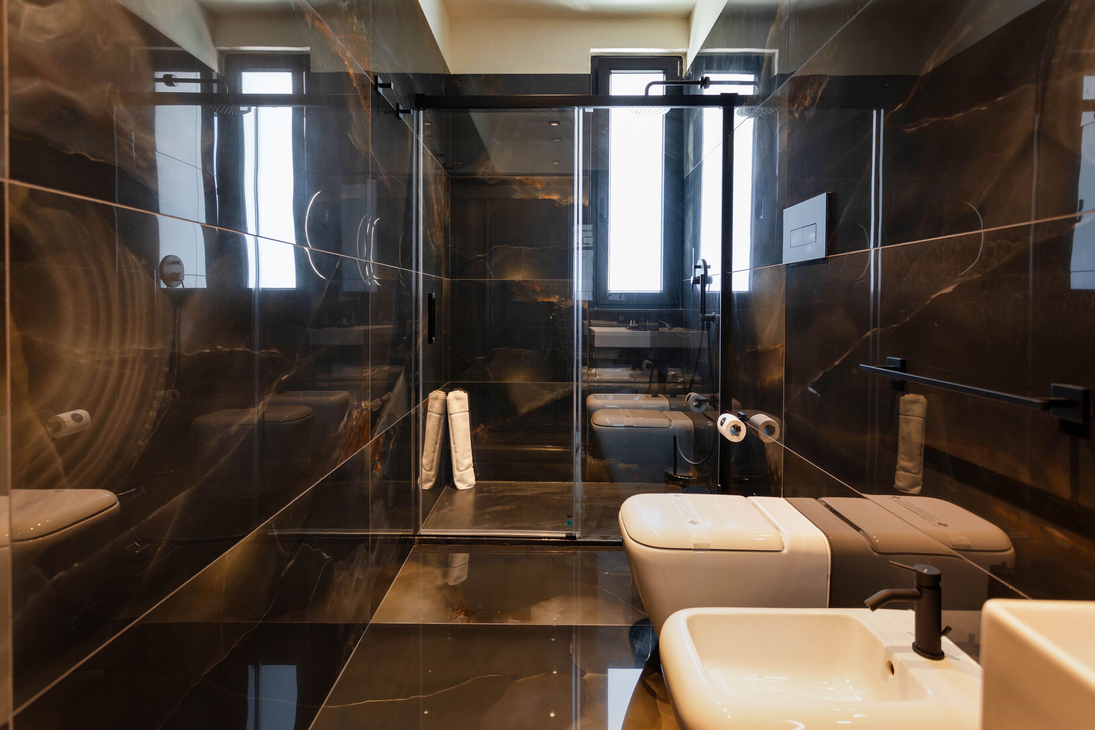 Un baño moderno con cabina de ducha de vidrio, inodoro y lavabo.