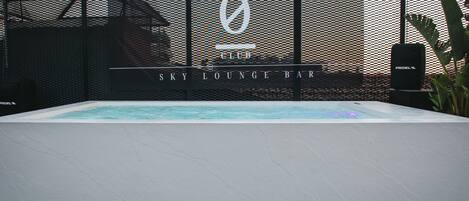 A pool area with a lounge bar named "Sky Lounge Bar" and a sign with a logo.