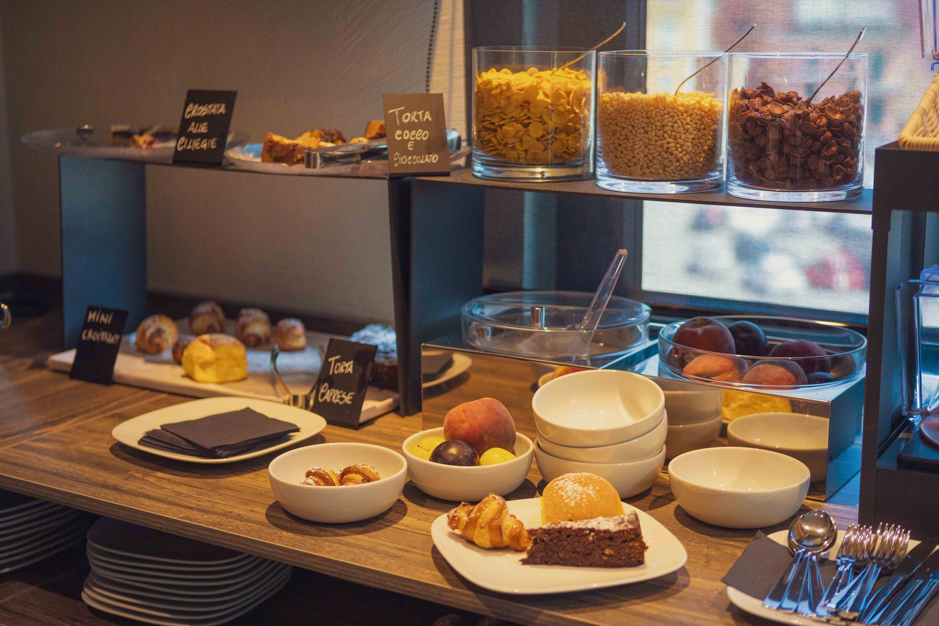 A breakfast buffet with various food items and labels in a cafe setting.