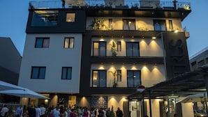 Un edificio moderno con diversi piani, posti a sedere all'aperto e un balcone con piante.