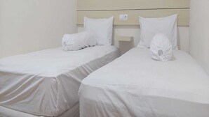 Two single beds with white bedding and headboards, a wooden headboard, and a light-colored wall. - Capital O 93489 An Nur Homestay Syariah (Mungkid)